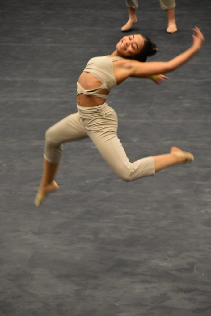 A performers from the Reynoldsburg High School Winter Guard in mid leap across the floor during the 2023 OIPA Central Crossing competition. 