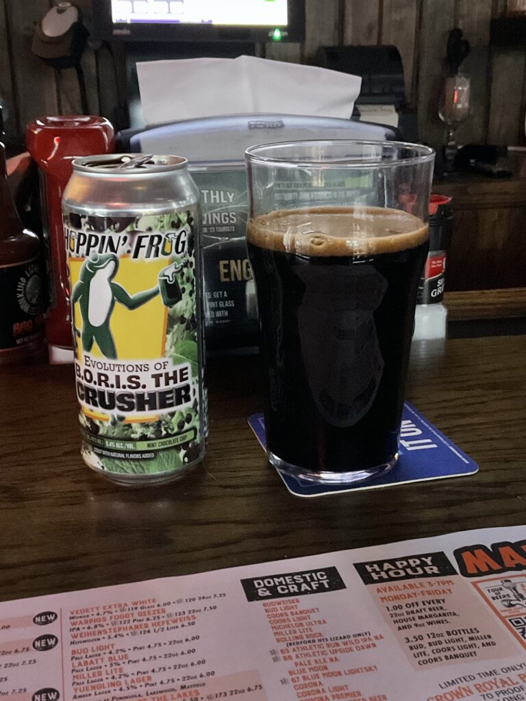 A glass of Hoppin Frog B.O.R.I.S. The Crusher mint chocolate chip imperial stout on the bar at the Winking Lizard. The beer’s cab is next to the glass. 