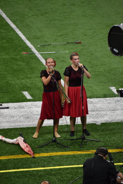 Two members of the 2019 Les Stentors drum and bugle corps, singing as part of their performance at the Drum Corps International World Championships in Indianapolis, Indiana.