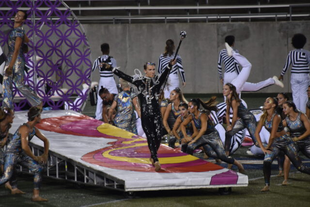 A member of the 2021 Bluecoats drum and bugle corps coming down a prop during their performance of Lucy
