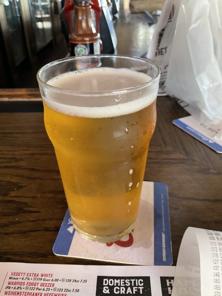 A glass of Ciderboys Peach County cider. The beer is amber, almost peachy, in color, with a thin head of white bubbles on top. 