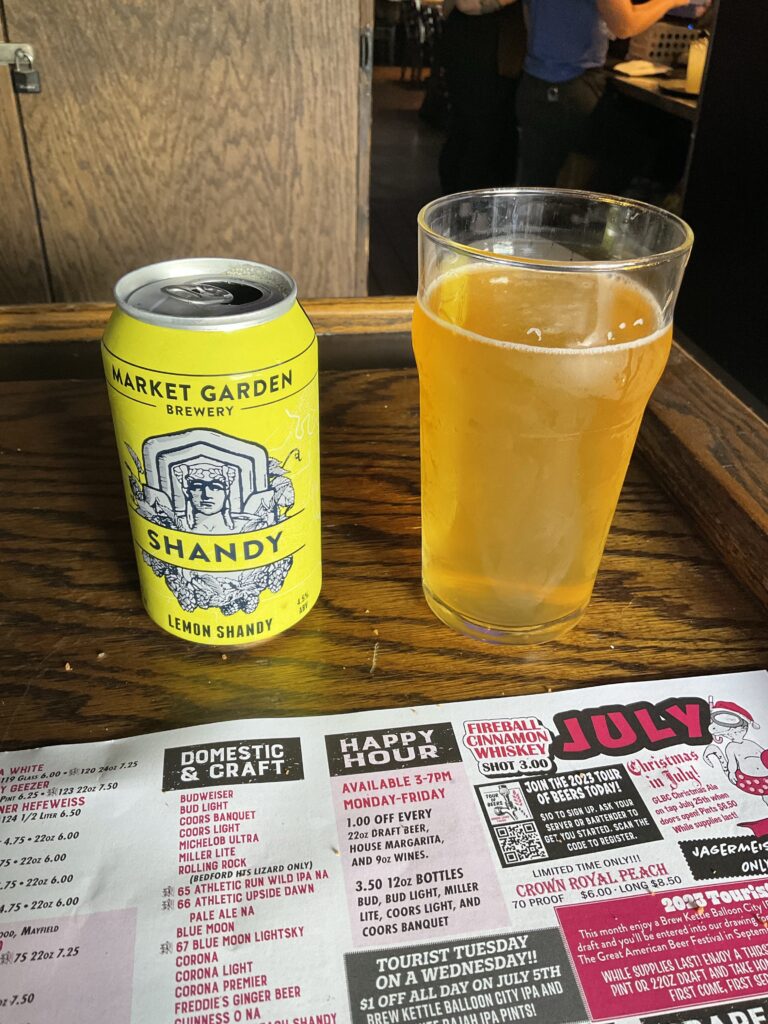 A glass of Market Garden lemon shandy. The beer is amber colored and slightly translucent. 